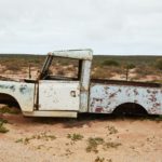 rusty abandoned car near fence in desert